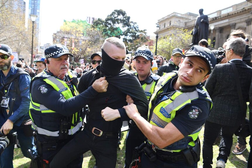 A man is taken away by Victoria Police after he refused to take off a mask during a rally in Melbourne