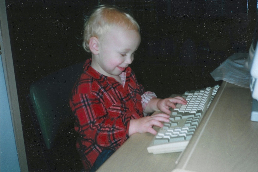 A toddler types on a keyboard.