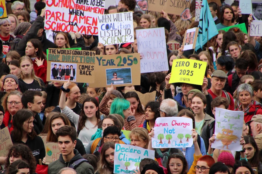 A closeup of a crowd of young people holding climate change signs.