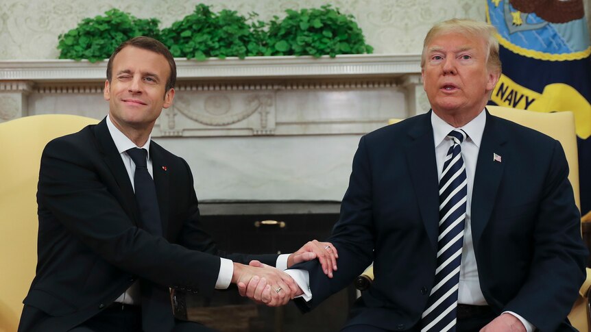 French President Emmanuel Macron winks while shaking Donald Trump's hand in the Oval Office.