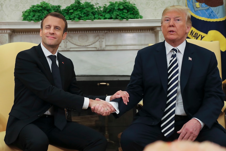 French President Emmanuel Macron winks while shaking Donald Trump's hand in the Oval Office.