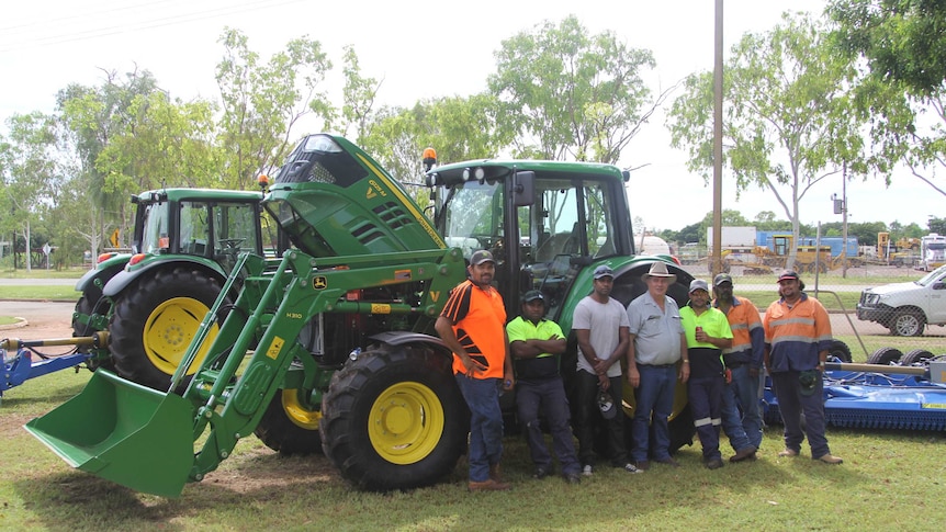 a group of men standing in front of a green tractor