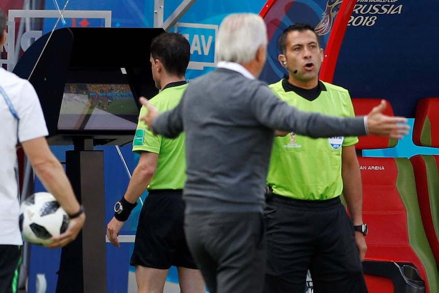 A referee looks at a computer screen reviewing a match decision.