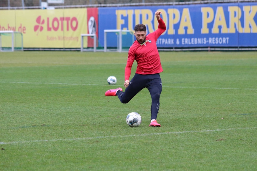 A footballer lines up to kick a ball.