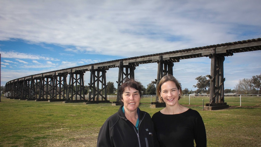 Two woman stand in front of an historic rail viaduct in Manilla NSW