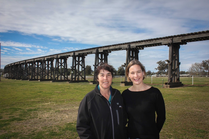 Two woman stand in front of an historic rail viaduct in Manilla NSW
