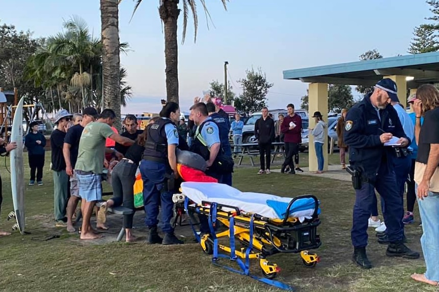 people standing a person while a stretcher is prepared 