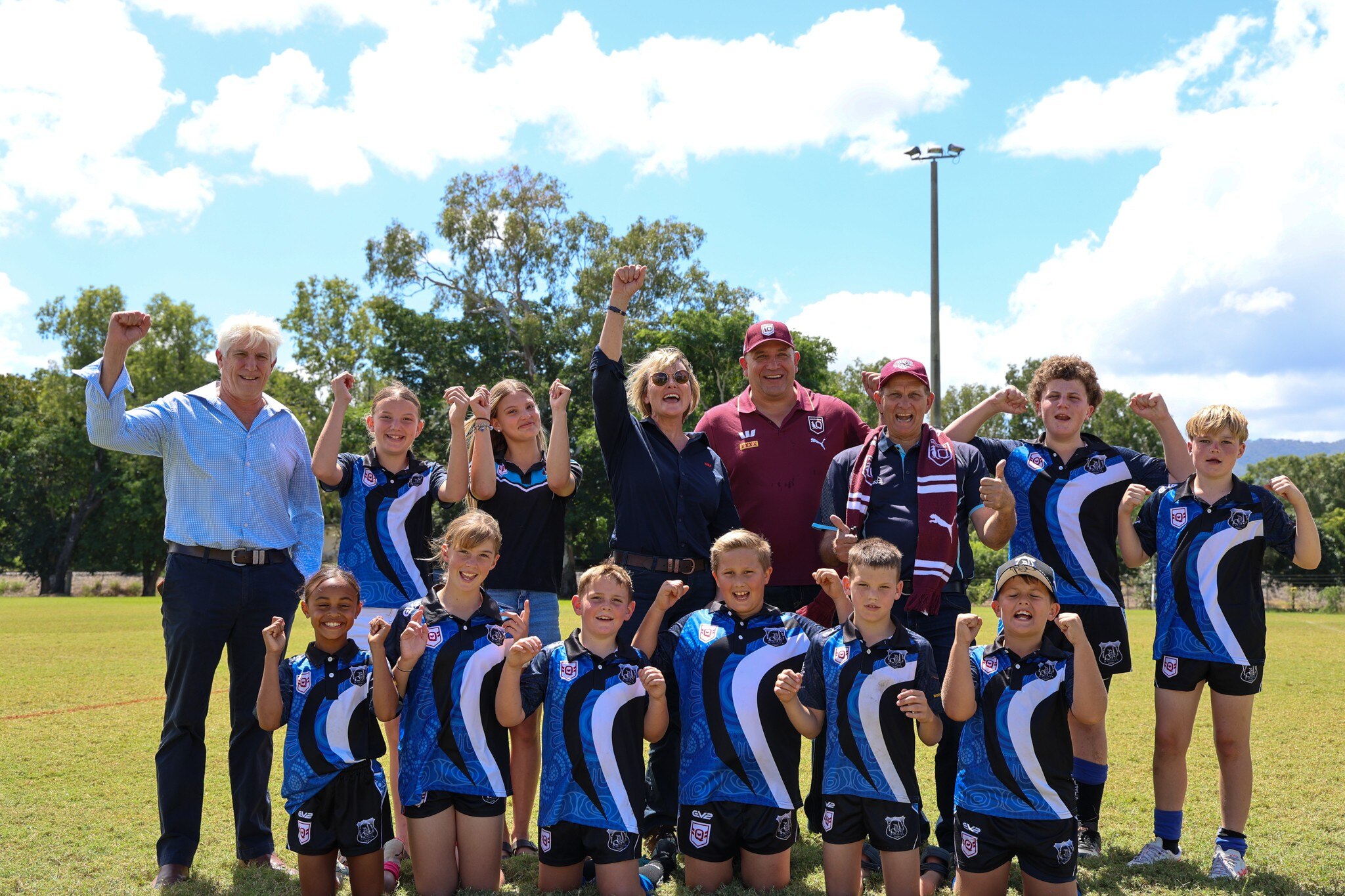 Photo of a footy team and some people in suits posing and cheering