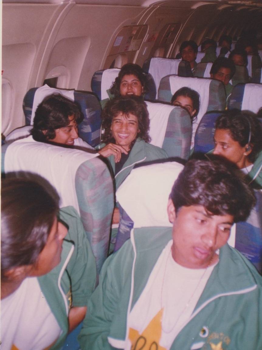 players smile and chat as they sit in their seats on a plane