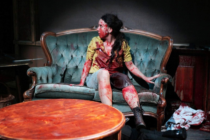 A woman onstage covered in fake blood