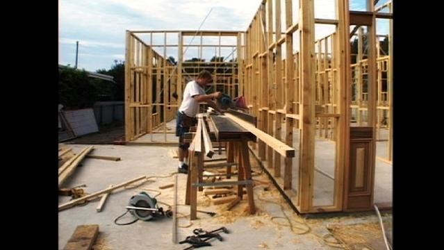 Man cuts wood at large table on house construction site