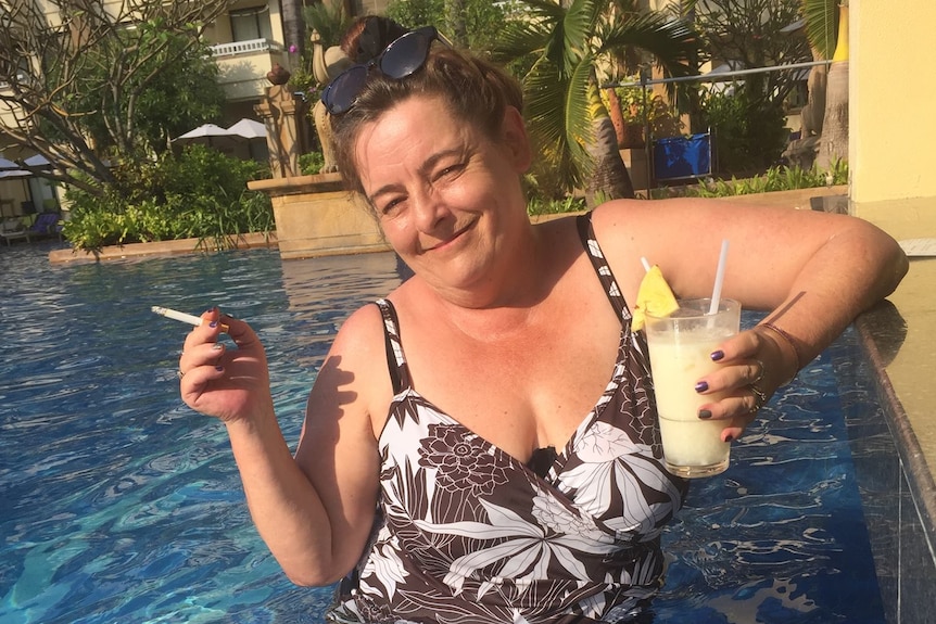 Polly Richardson relaxing in a pool, with a cocktail in one hand and a cigarette in the other.