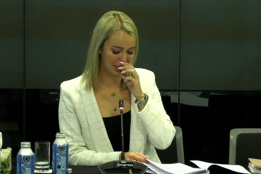 A woman speaks into a microphone at an inquiry.
