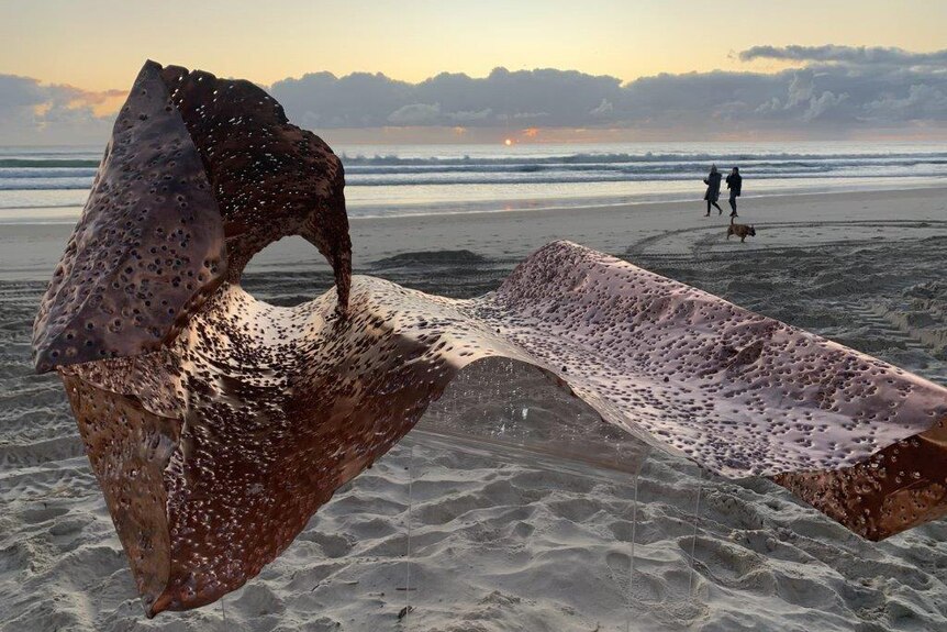 A copper sculpture at dawn on Currumbin Beach