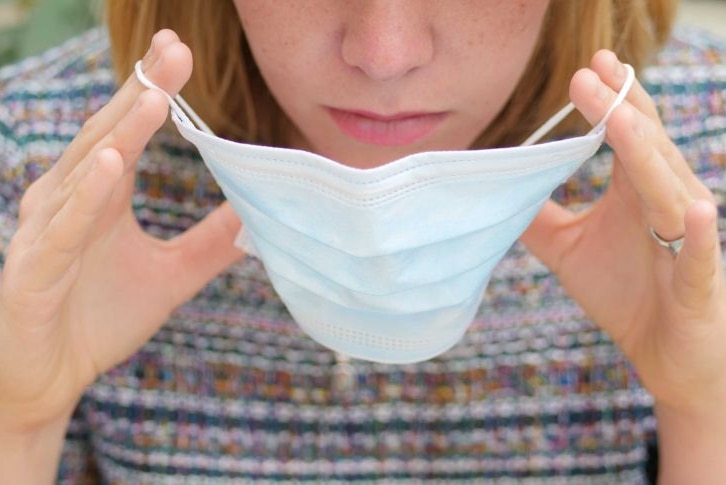 A close-up of a woman putting on a mask.