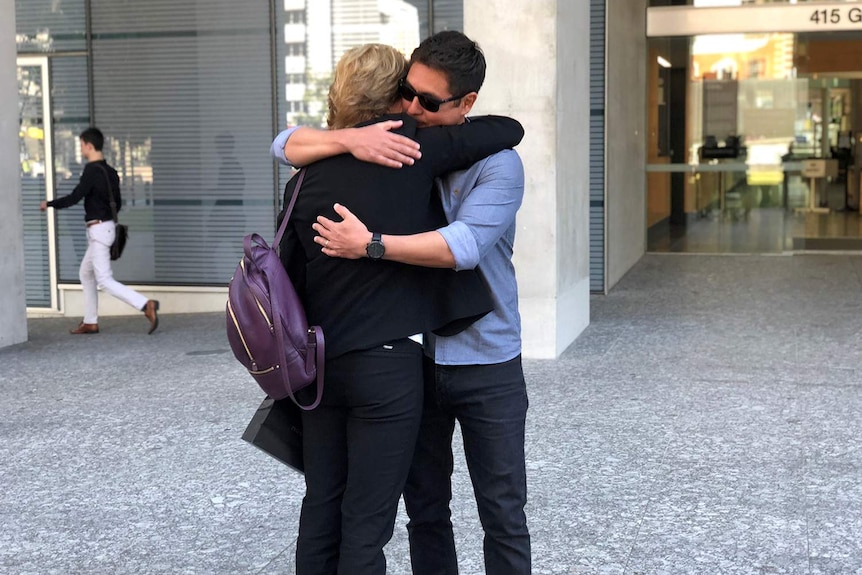 Brother of Fabiana Palhares, Raphael Pahlares, hugs a supporter outside the Supreme Court in Brisbane.