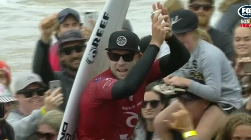Mick Fanning claps as he is chaired up Bells Beach by fans.
