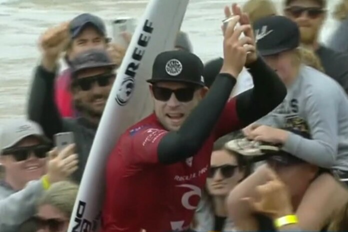 Mick Fanning claps as he is chaired up Bells Beach by fans.
