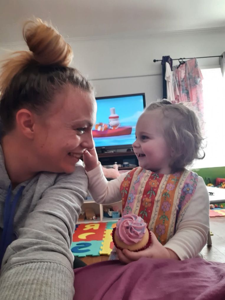 Una mujer mira de reojo y sonríe a un pequeño niño rubio en el salón de una casa.