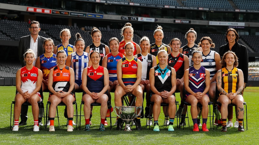 Photo of all 18 AFLW club captains plus Travis Auld and Nicole Livingstone from the AFL. Players are seated at Marvel stadium