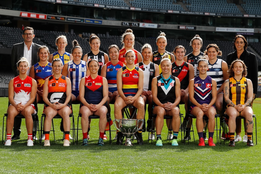 Photo of all 18 AFLW club captains plus Travis Auld and Nicole Livingstone from the AFL. Players are seated at Marvel stadium