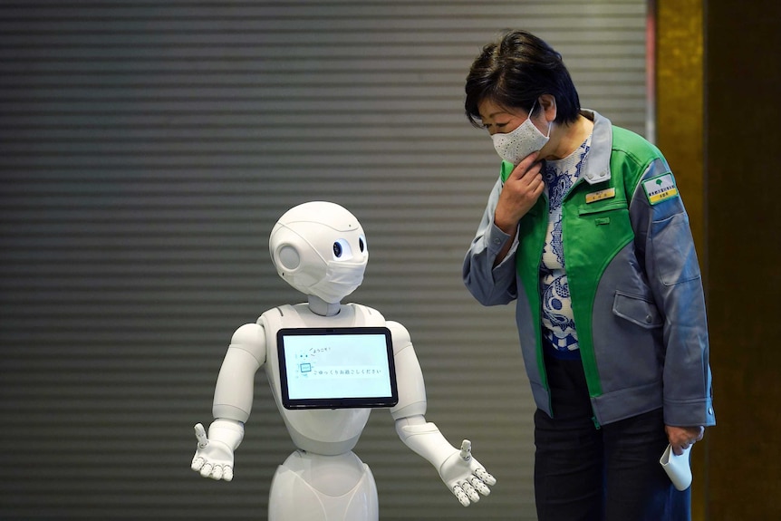 A humanoid robot Pepper wearing a face mask greets Tokyo's governor.