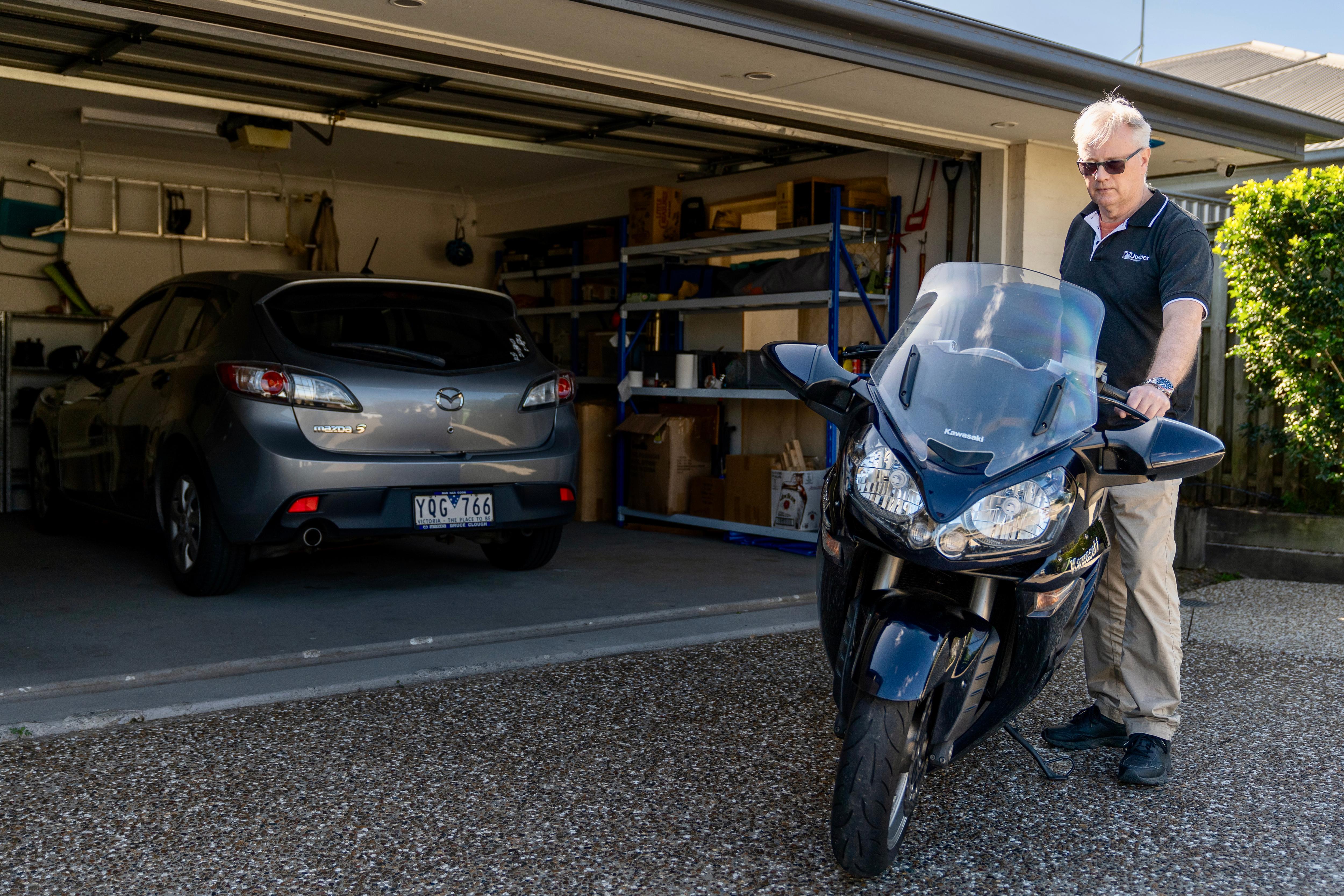 Napoleon Burnell holding up a motorbike outside the garage near his home.