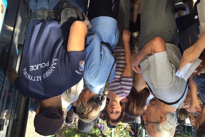 Greek pensioners are escorted by police into banks