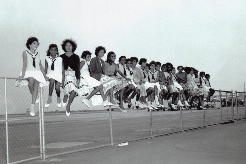 Cherbourg marching girls sit on a fence at Eagle Farm Airport in Brisbane waiting to fly to Melbourne in 1962.