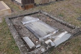 A grave lies flat on the ground in pieces