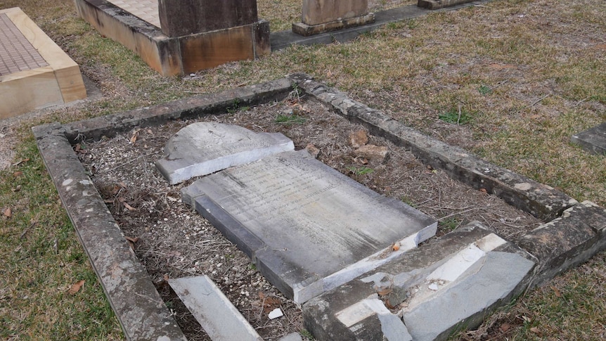 A grave lies flat on the ground in pieces