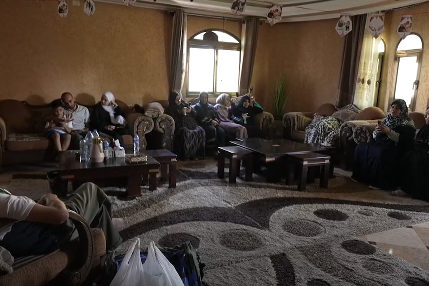 Members of a family sitting in a large living room in darkness.