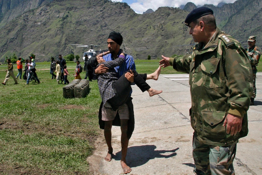 A man carries a flood-affected victim after they were rescued in the Himalayan state of Uttarakhand.