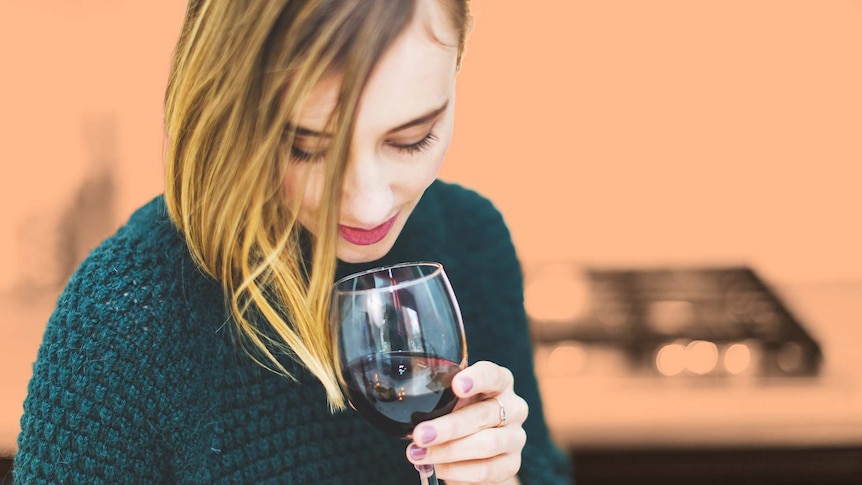 Young woman with a glass of red wine in her hand to illustrate a dinner party.