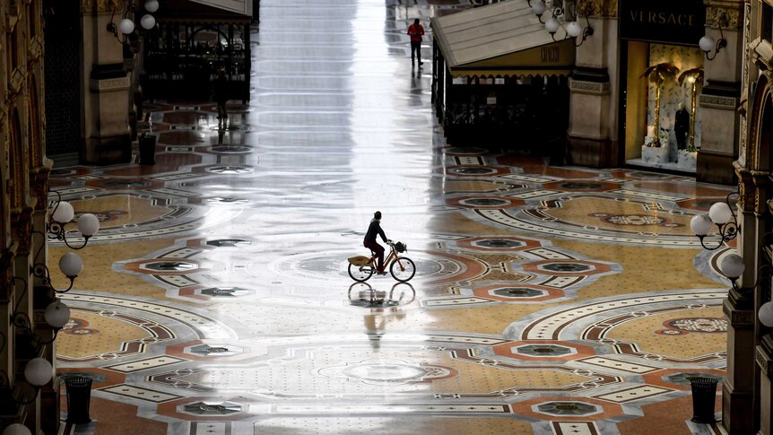 A person on a bike in an empty shopping arcade