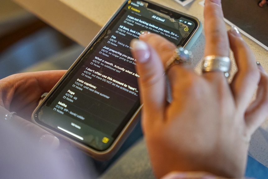 A woman's hand scrolls notes on a phone.