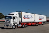 A white truck tows two refrigerated containers. 