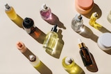 An array of clear dropped bottles of different colours, on cream surface,  taken from above