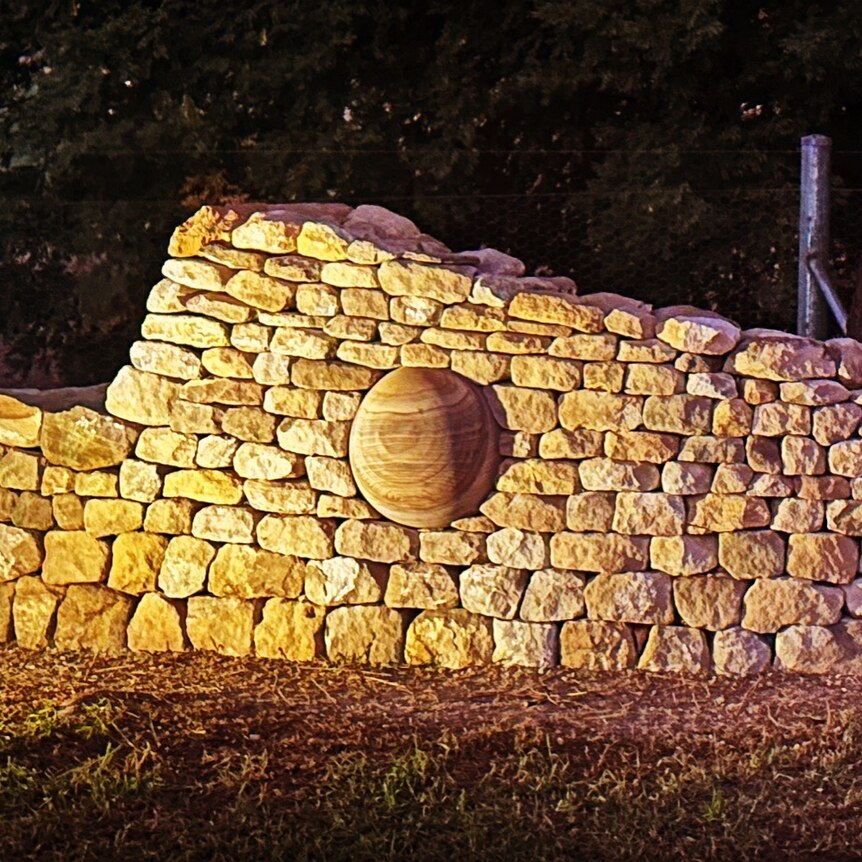 A dry stone wall at night time illuminated. 