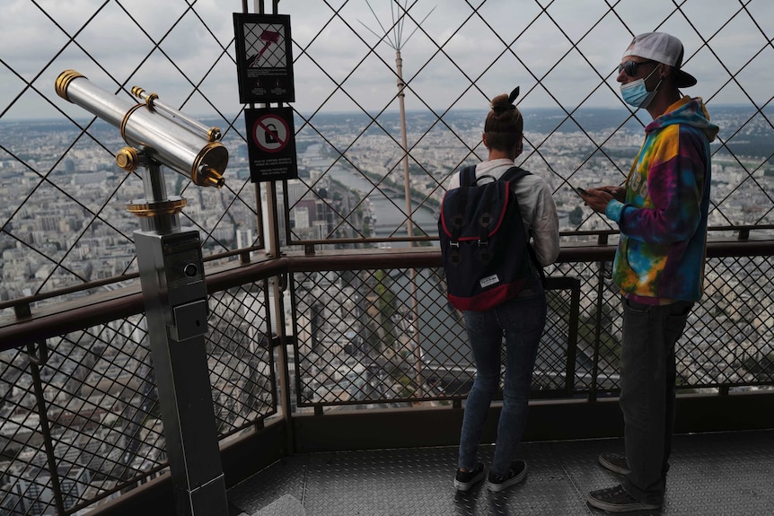 Visitors look on from the third level during the opening up of the top floor of the Eiffel Tower.