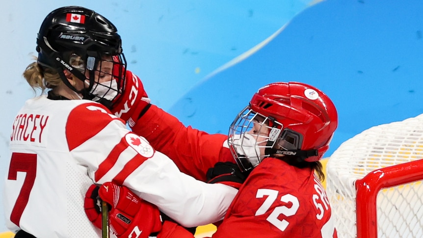Laura Stacey of Canada and Anna Savonina of the ROC Team fight for the puck in their ice hockey match at the Beijing Olympics