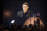 A giant screen displays the image of Edward Snowden