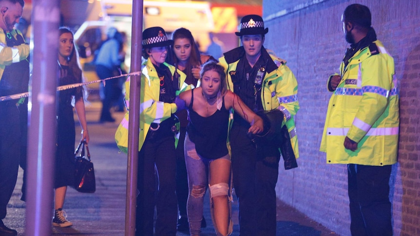 UK police escort an injured woman outside Manchester Arena after reports of an explosion.