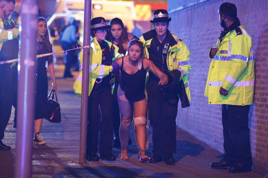 UK police escort an injured woman outside Manchester Arena after reports of an explosion.