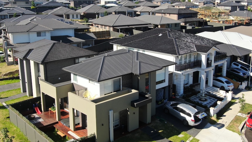 An aerial shot shows a relatively new house in the foreground, with other similar houses behind.