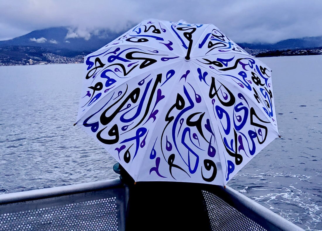 A woman holding an umbrella covered in Arabic calligraphy
