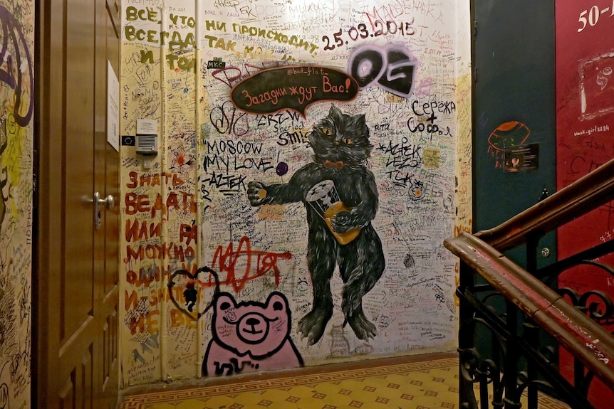 A staircase covered with graffiti in Russian and a drawing of a cat.