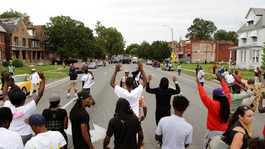 Protestors hold their hands up as police approach them in the streets after a shooting incident in St. Louis, Missouri