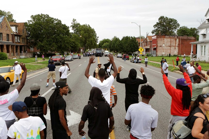 Protestors hold their hands up as police approach them in the streets after a shooting incident in St. Louis, Missouri