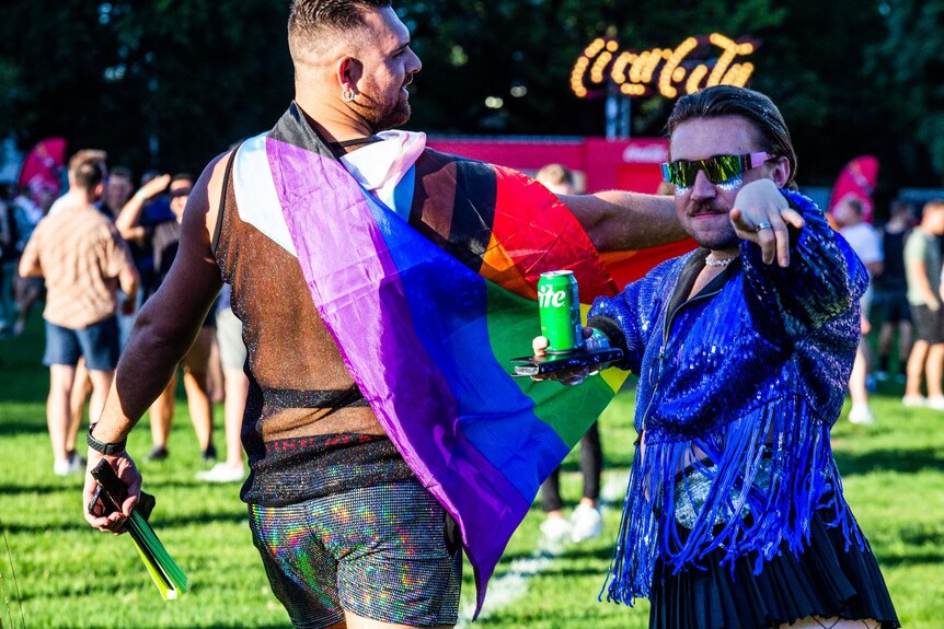 two men one dressed with a shiny jacket out on a field waiting f or a concert